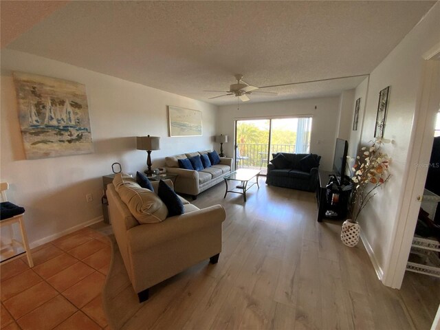 living room with ceiling fan, a textured ceiling, and light hardwood / wood-style flooring