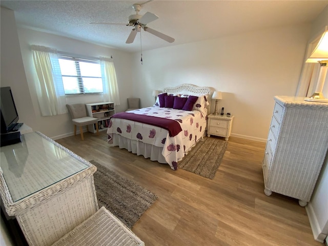 bedroom with light wood-type flooring, a textured ceiling, and ceiling fan