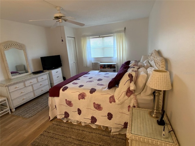 bedroom with ceiling fan, wood-type flooring, and a closet