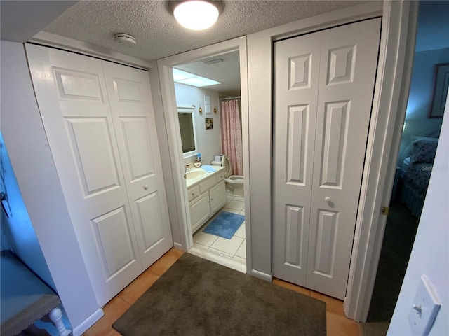 bathroom featuring a textured ceiling, toilet, tile patterned floors, and vanity