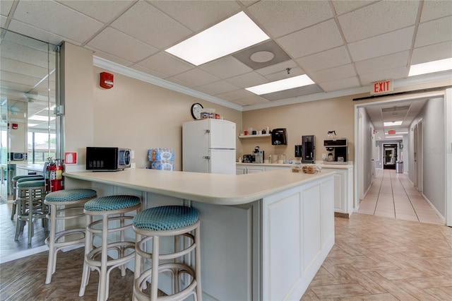 kitchen featuring kitchen peninsula, crown molding, white refrigerator, white cabinets, and light parquet floors