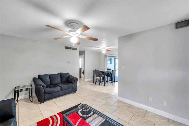 tiled living room with ceiling fan and a textured ceiling