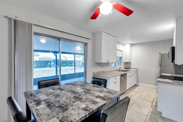 kitchen featuring sink, light stone counters, light tile patterned floors, stainless steel appliances, and white cabinets