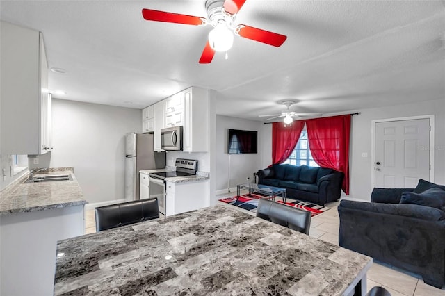 dining area featuring ceiling fan, sink, light tile patterned floors, and a textured ceiling