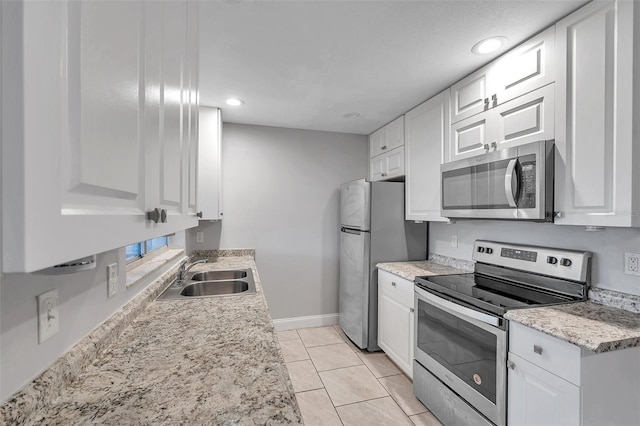 kitchen featuring sink, light tile patterned floors, white cabinetry, stainless steel appliances, and light stone countertops