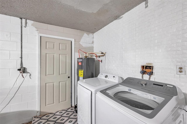 laundry room featuring brick wall, washing machine and dryer, and water heater