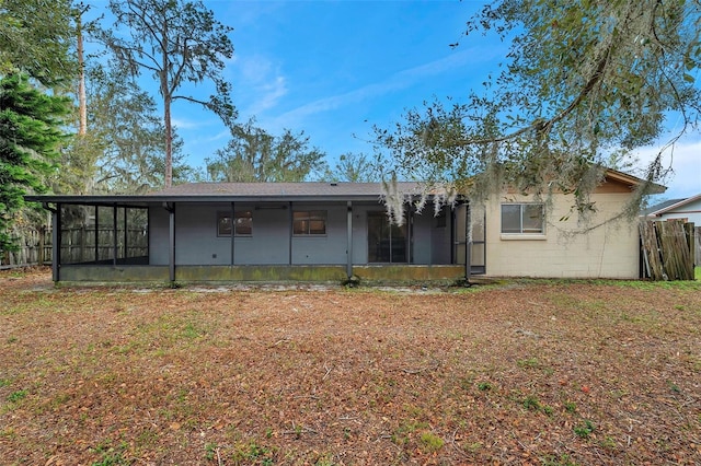 back of property with a sunroom and a lawn