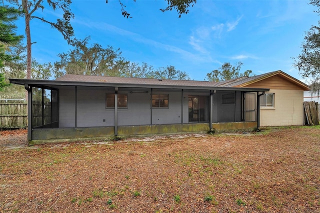 rear view of house featuring a lawn and a sunroom