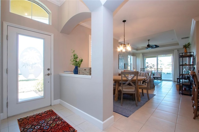 entrance foyer featuring light tile patterned flooring, a tray ceiling, crown molding, and a chandelier