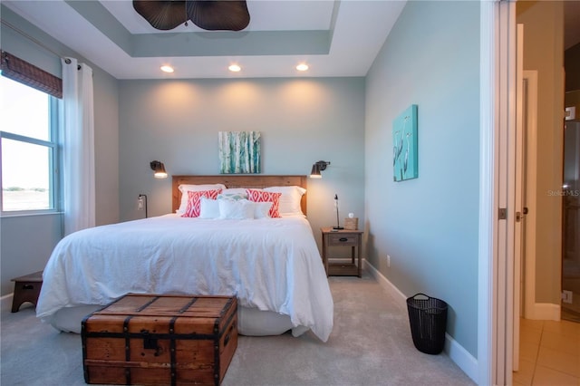 carpeted bedroom with ceiling fan and a tray ceiling