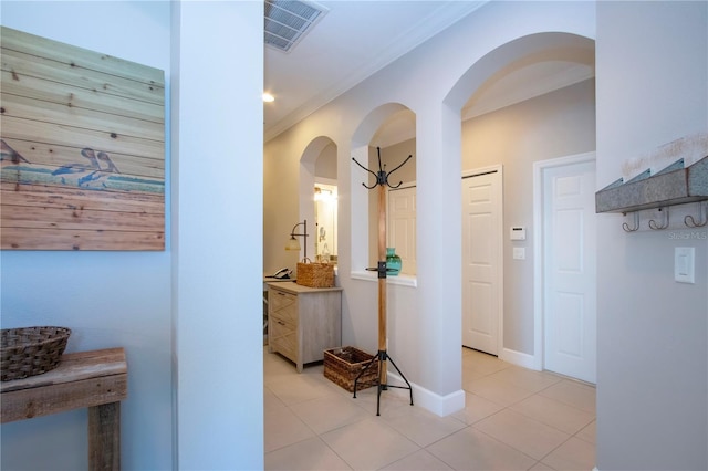 corridor with light tile patterned floors and crown molding