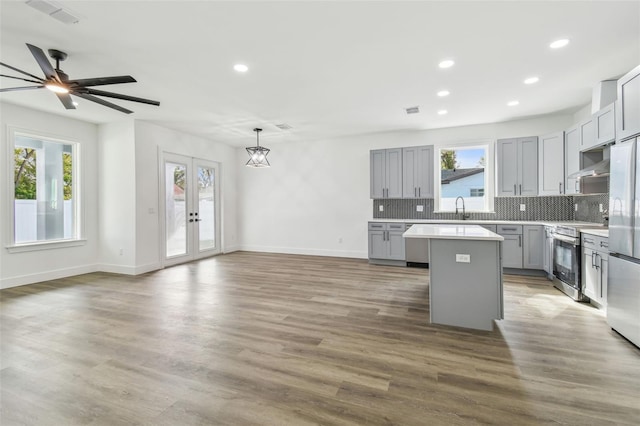 kitchen featuring decorative light fixtures, a center island, stainless steel appliances, and gray cabinets