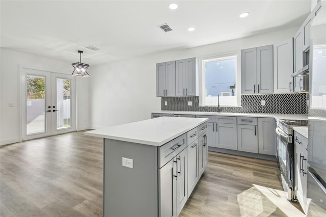 kitchen featuring pendant lighting, gray cabinetry, stainless steel range oven, and a kitchen island