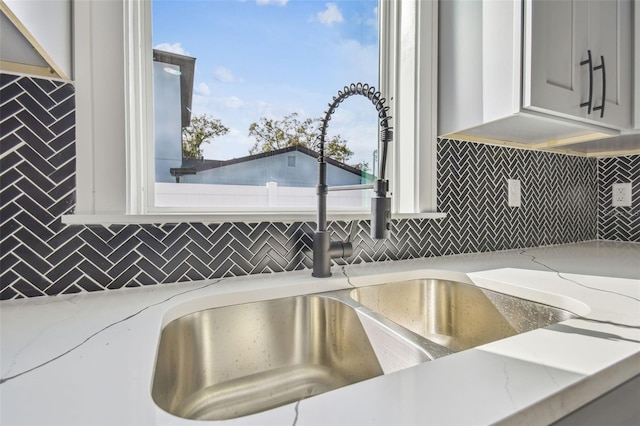 interior details with tasteful backsplash, sink, and light stone counters