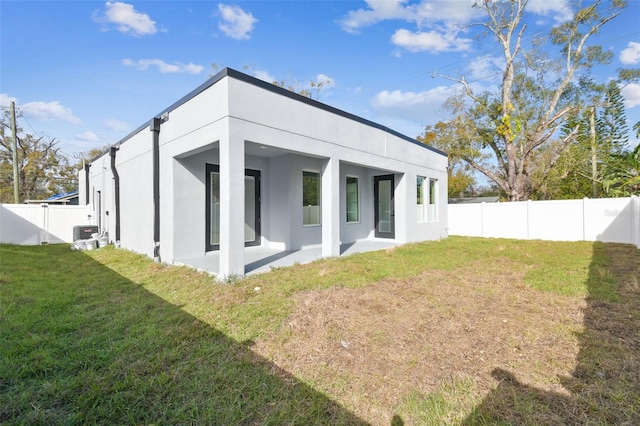 rear view of house featuring central AC, a lawn, and a patio