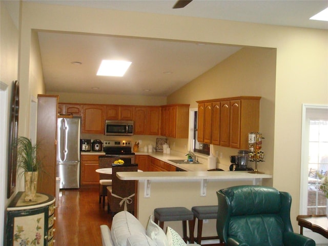 kitchen featuring dark wood-type flooring, sink, a breakfast bar area, appliances with stainless steel finishes, and kitchen peninsula