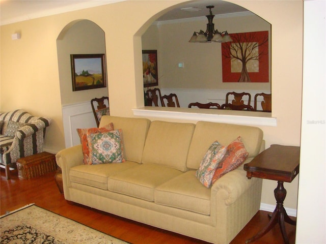 living room featuring crown molding, wood-type flooring, and a chandelier