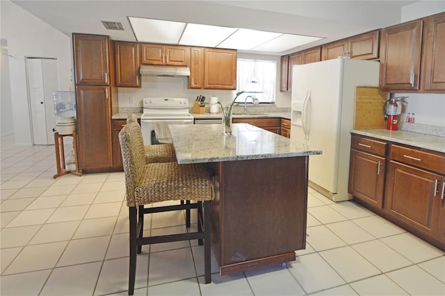 kitchen featuring white appliances, a kitchen bar, a center island, and sink