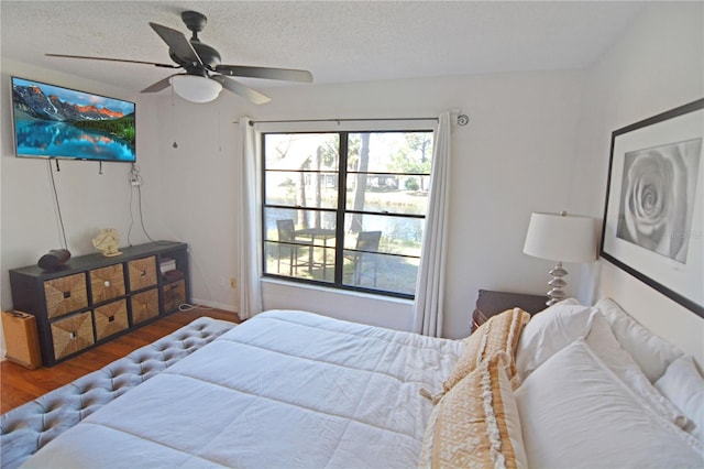 bedroom with dark wood-type flooring, ceiling fan, and a textured ceiling