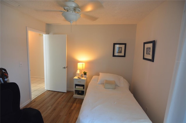 bedroom featuring ceiling fan, hardwood / wood-style floors, and a textured ceiling