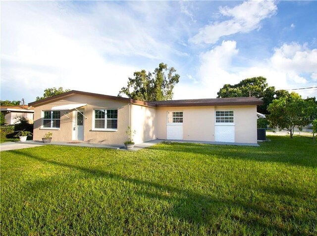 single story home featuring a front lawn, stucco siding, and central AC unit
