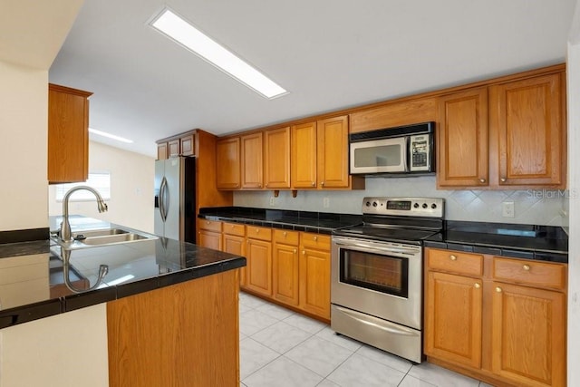 kitchen featuring light tile patterned flooring, lofted ceiling, sink, appliances with stainless steel finishes, and decorative backsplash