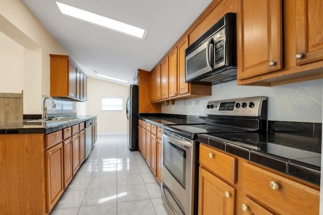 kitchen with tasteful backsplash, appliances with stainless steel finishes, sink, and light tile patterned floors