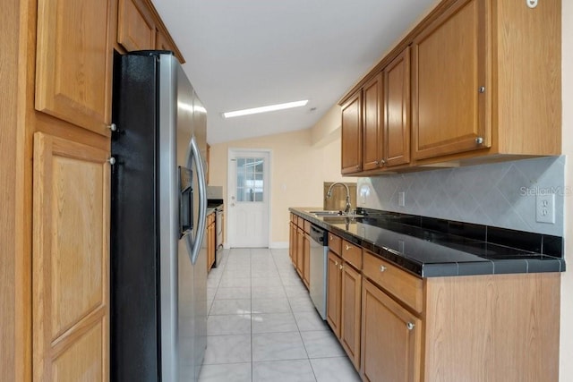 kitchen featuring light tile patterned flooring, appliances with stainless steel finishes, vaulted ceiling, tasteful backsplash, and sink