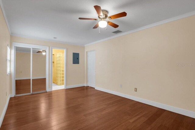 unfurnished bedroom with ensuite bath, ornamental molding, electric panel, hardwood / wood-style flooring, and ceiling fan