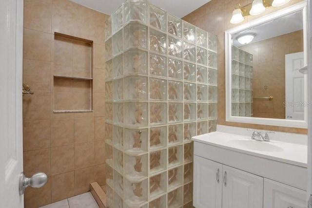 bathroom featuring a tile shower, vanity, and tile walls