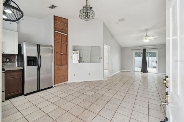 kitchen with vaulted ceiling, white cabinetry, stainless steel fridge with ice dispenser, light tile patterned floors, and tasteful backsplash