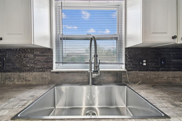 room details featuring sink, white cabinetry, and tasteful backsplash