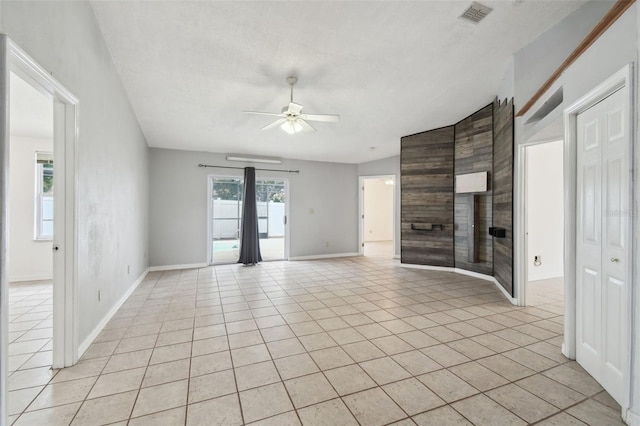 unfurnished living room with ceiling fan, light tile patterned floors, and vaulted ceiling