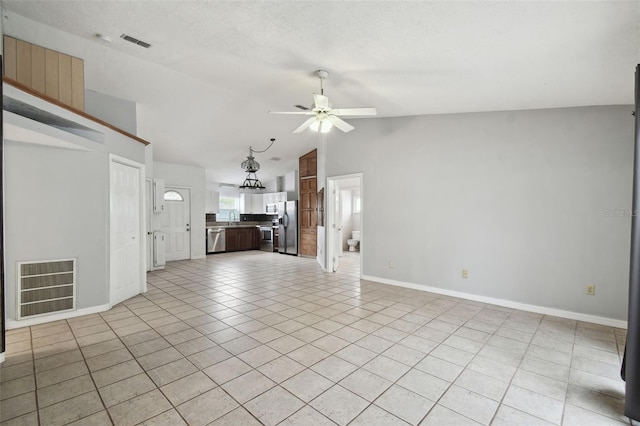 unfurnished living room featuring a textured ceiling, light tile patterned floors, sink, ceiling fan, and lofted ceiling