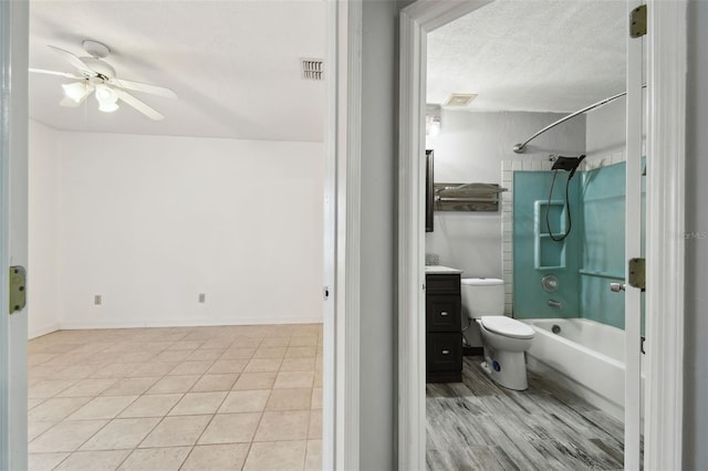 full bathroom featuring toilet, a textured ceiling, shower / bathing tub combination, vanity, and ceiling fan