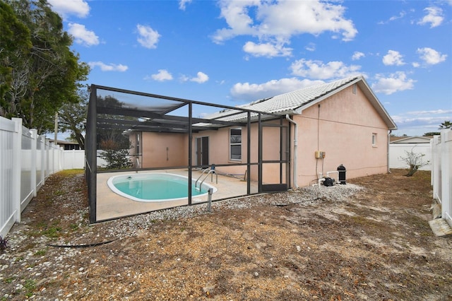 rear view of house featuring glass enclosure, a fenced in pool, and a patio