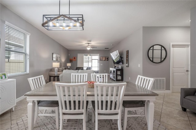 tiled dining area with ceiling fan with notable chandelier