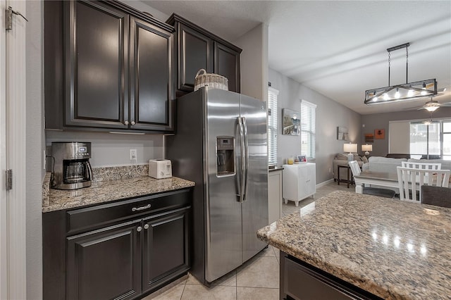 kitchen featuring light tile patterned flooring, light stone countertops, stainless steel fridge with ice dispenser, and hanging light fixtures