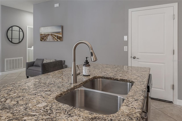 kitchen featuring stone counters, light tile patterned flooring, and sink