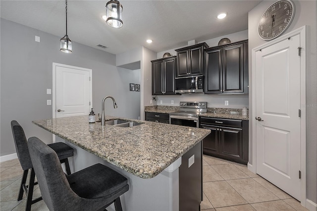 kitchen with light tile patterned flooring, sink, an island with sink, pendant lighting, and stainless steel appliances