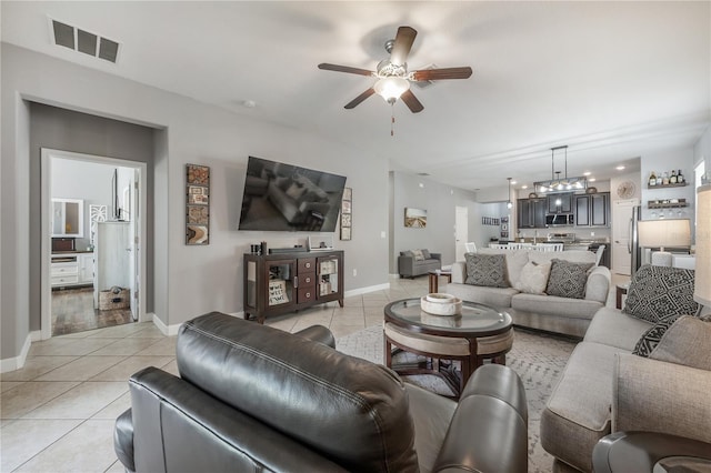 tiled living room featuring ceiling fan with notable chandelier