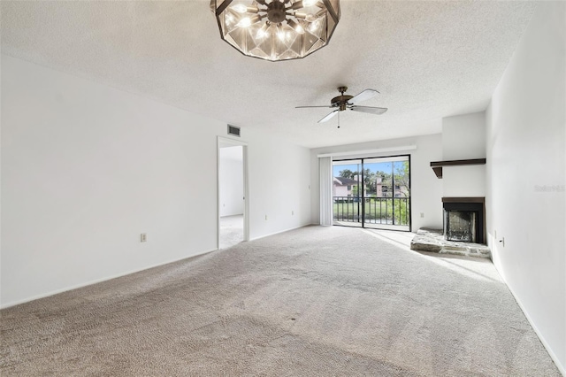 unfurnished living room with ceiling fan, carpet floors, a textured ceiling, and a fireplace