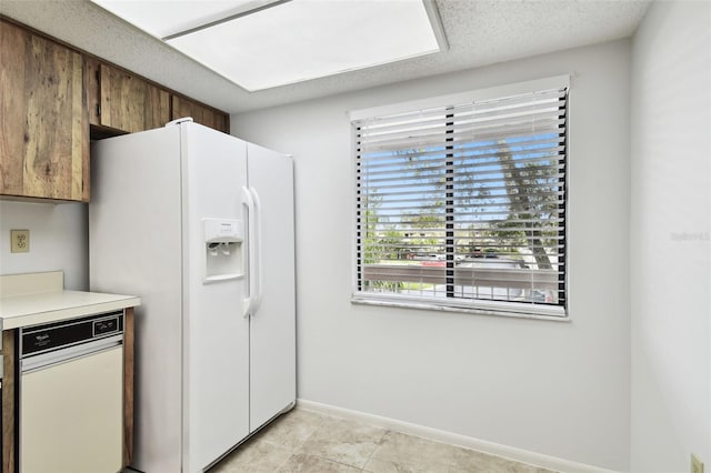 kitchen featuring white fridge with ice dispenser and a textured ceiling