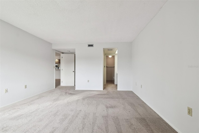 carpeted empty room with a textured ceiling