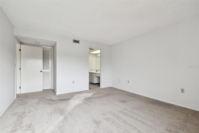 unfurnished bedroom with sink, carpet floors, a textured ceiling, and ensuite bathroom