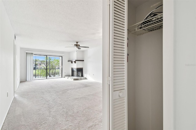 unfurnished living room featuring ceiling fan, carpet flooring, and a textured ceiling