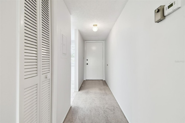 corridor with light colored carpet and a textured ceiling