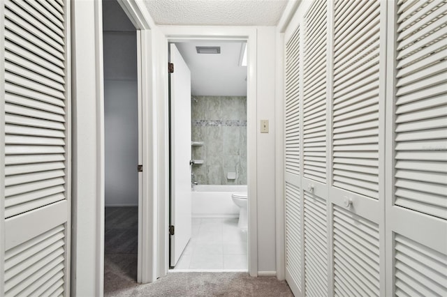 hall featuring light colored carpet and a textured ceiling