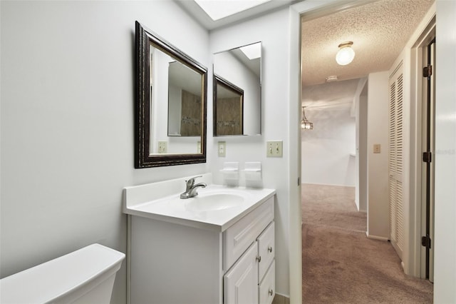 bathroom with vanity, toilet, and a textured ceiling