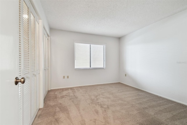 unfurnished bedroom with two closets, light colored carpet, and a textured ceiling